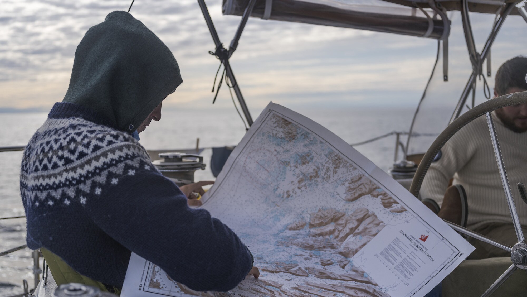 Explorer Mark Synnott studies a map aboard his ship, the Polar Sun, in the Arctic , Northwest Passage. (National Geographic for Disney/Renan Ozturk)