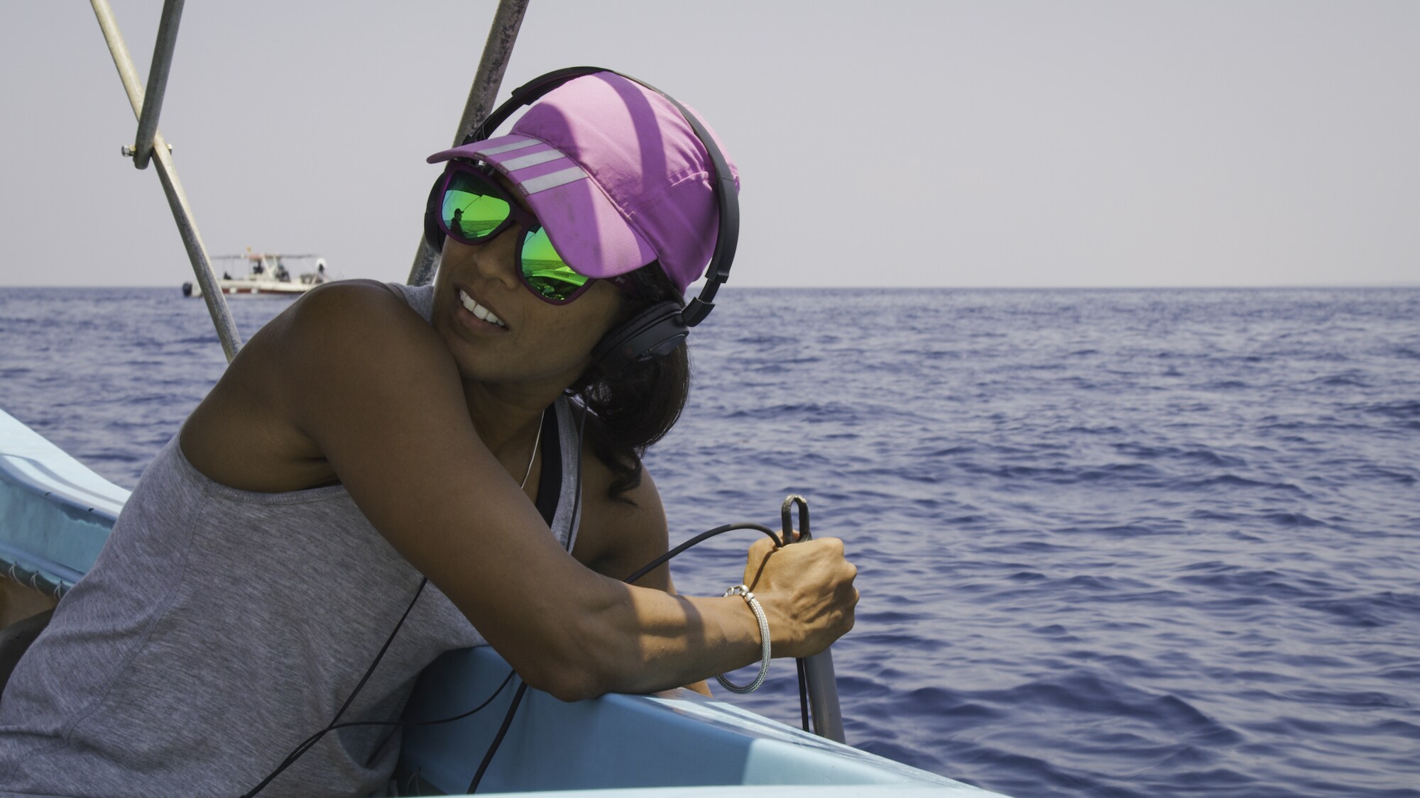 Marine biologist Asha DeVos listens to sperm whale conversations with a hydrophone. She is listening for dialects that separate whale populations. (National Geographic for Disney+/Andrew Mitchell)