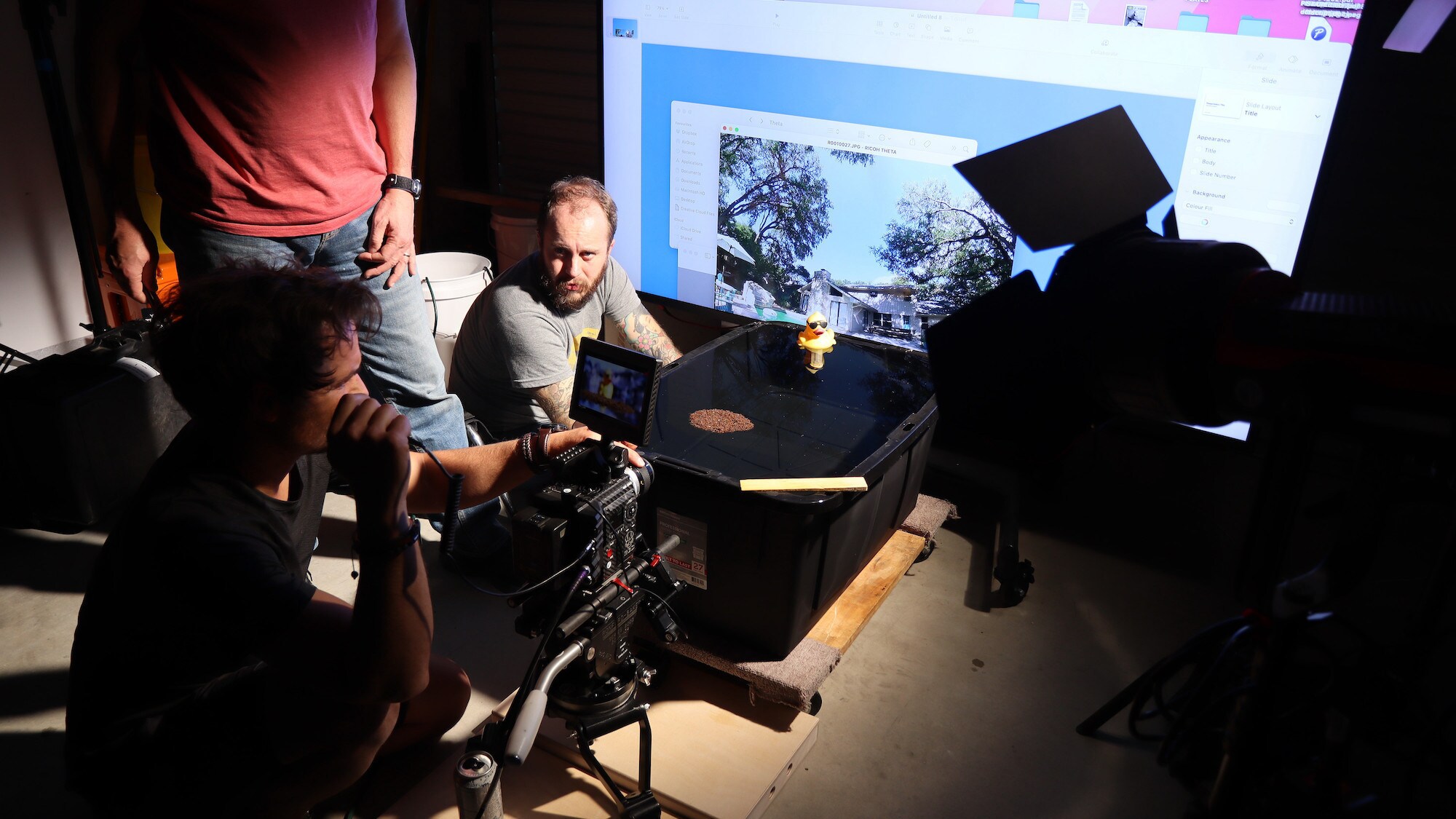 Director of Photography Alex Jones, lighting assistant Matt Langbehn and bug wrangler Sean O'Donnell set a shot of fire ants rafting in a tank in Buda, Texas for the "Braving the Backyard" episode of "A Real Bug's Life."  A plastic duck is included to provide perspective (showing how small the fire ants are) and a terrace and house are seen in the background backplate. (National Geographic/Alex Hemmingway)