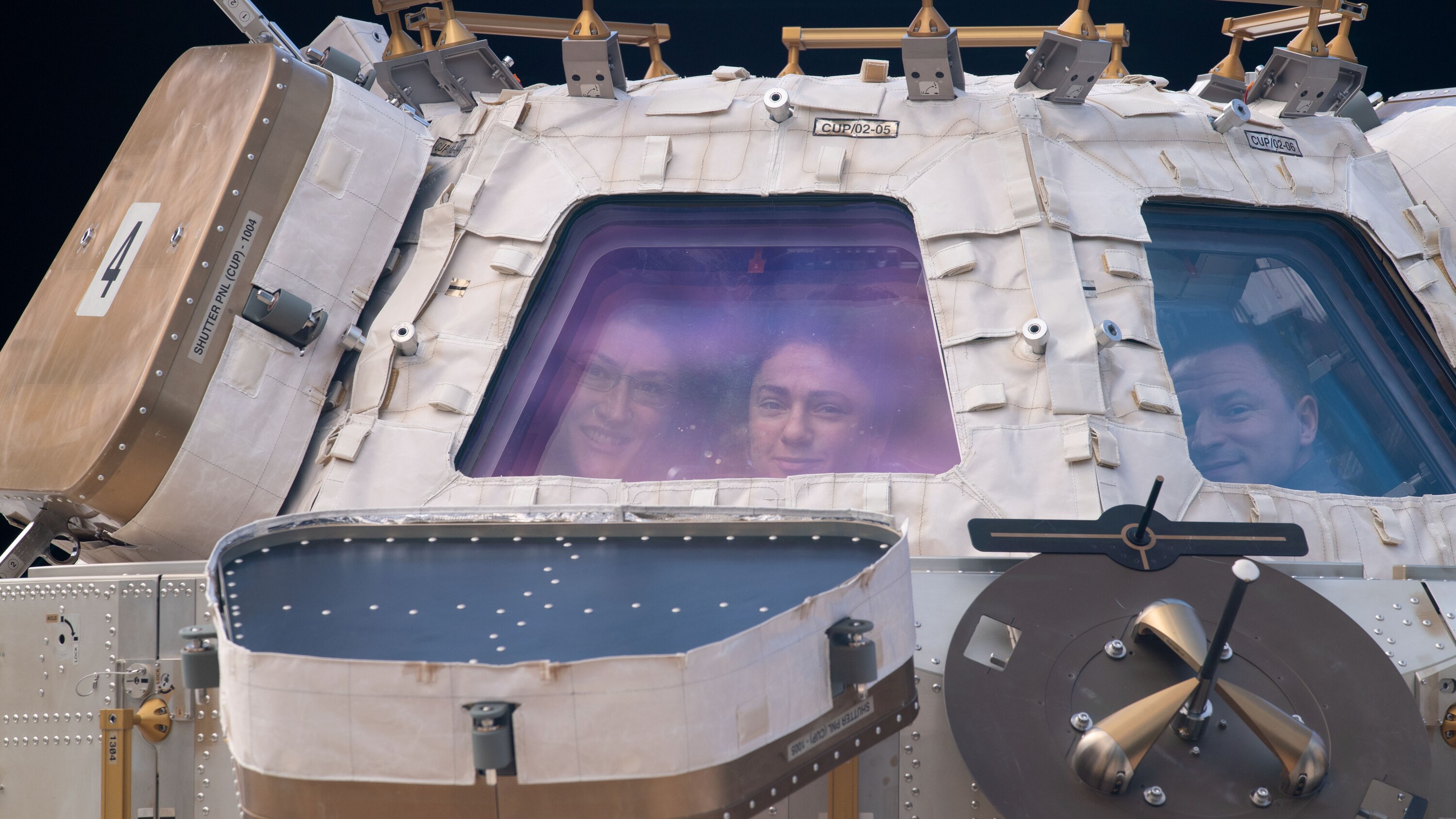 AMONG THE STARS - (Nov. 4, 2019) - NASA astronauts (from left) Christina Koch, Jessica Meir and Andrew Morgan peer through the International Space Station's "window to the world," the cupola. The trio were on robotics duty monitoring the arrival and capture of the Cygnus space freighter from Northrop Grumman. (NASA) CHRISTINA KOCH, JESSICA MEIR, ANDREW MORGAN