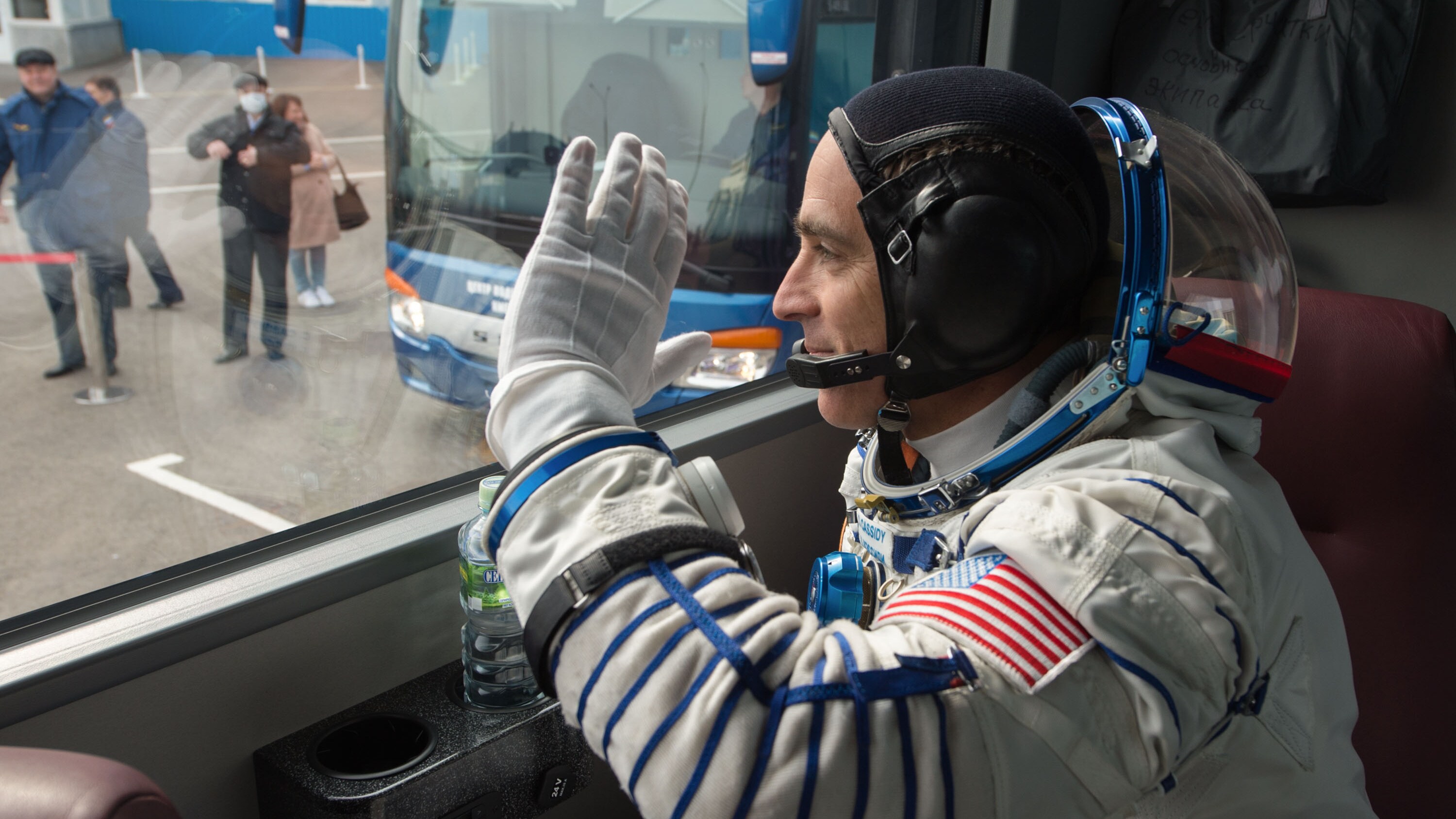 AMONG THE STARS - Expedition 63 crewmember Chris Cassidy of NASA waves farewell as he, Anatoly Ivanishin, and Ivan Vagner of Roscosmos depart building 254 via bus for the launch pad, Thursday, April 9, 2020 at the Baikonur Cosmodrome in Kazakhstan. A few hours later, they lifted off on a Soyuz rocket for a six-and-a-half month mission on the International Space Station. (NASA/GCTC/Andrey Shelepin) CHRIS CASSIDY