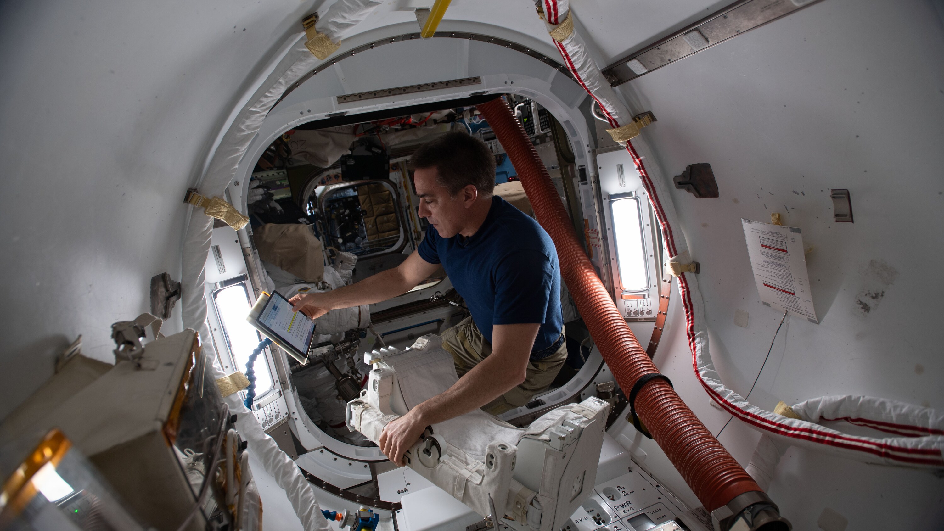 AMONG THE STARS - (June 24, 2020) - NASA astronaut and Expedition 63 Commander Chris Cassidy reviews maintenance procedures on a computer while working on U.S. spacesuit components inside the International Space Station's Quest airlock. (NASA) CHRIS CASSIDY