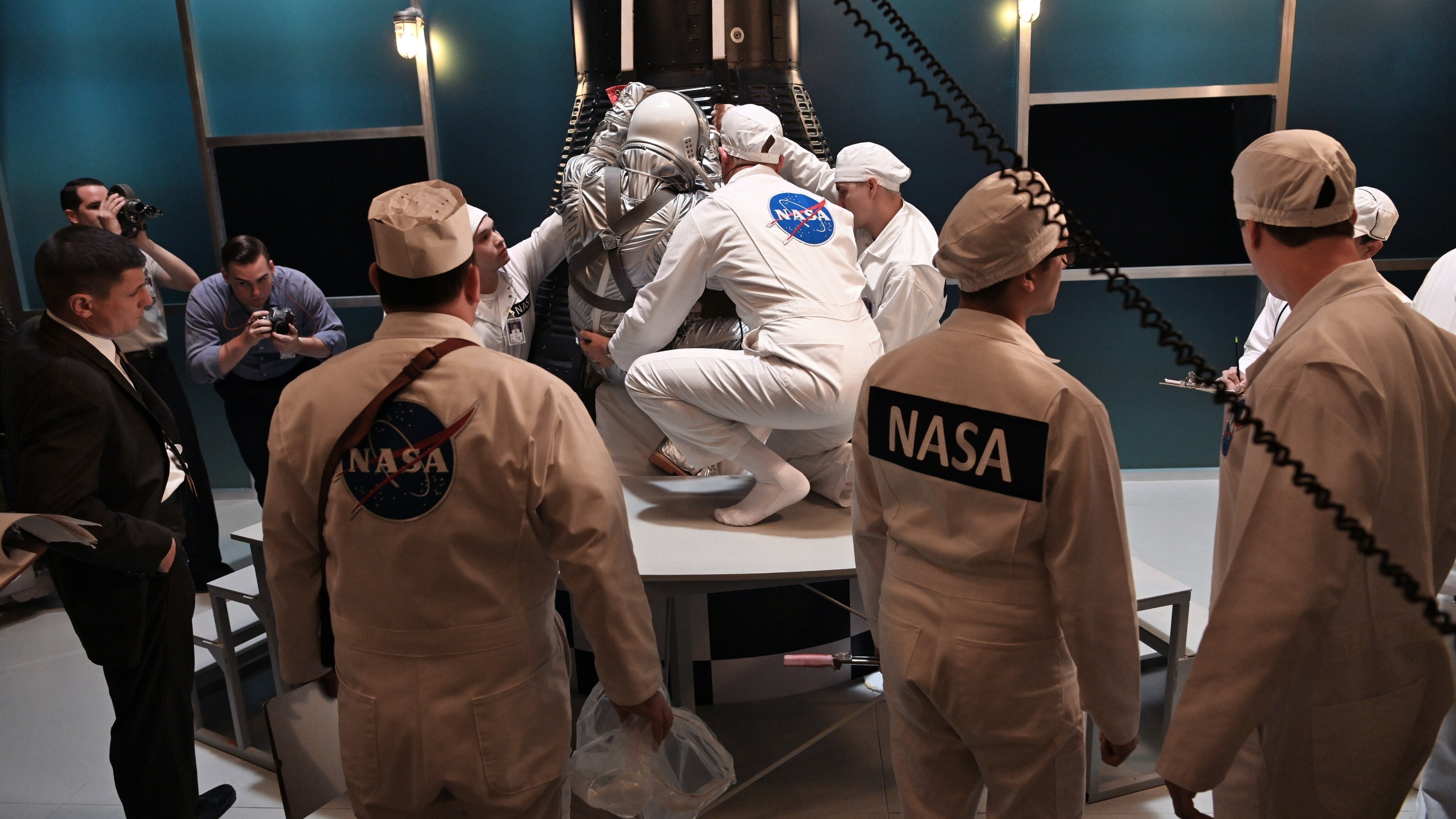 Alan Shepard (standing left)  played by Jake McDorman prepares to enter the Mercury capsule with the assistance of John Glenn (center) played by Patrick J. Adams in National Geographic's THE RIGHT STUFF streaming on Disney+. (Credit: National Geographic/Gene Page)