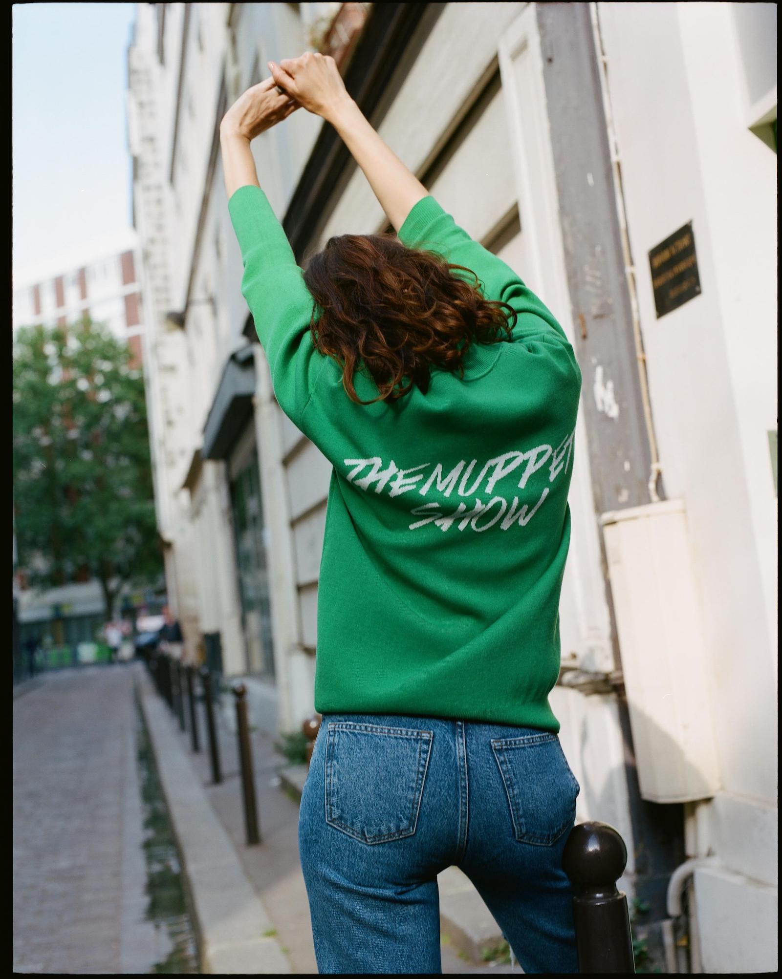 Model wearing green sweatshirt with text "The Muppet Show" from the Sandro collection