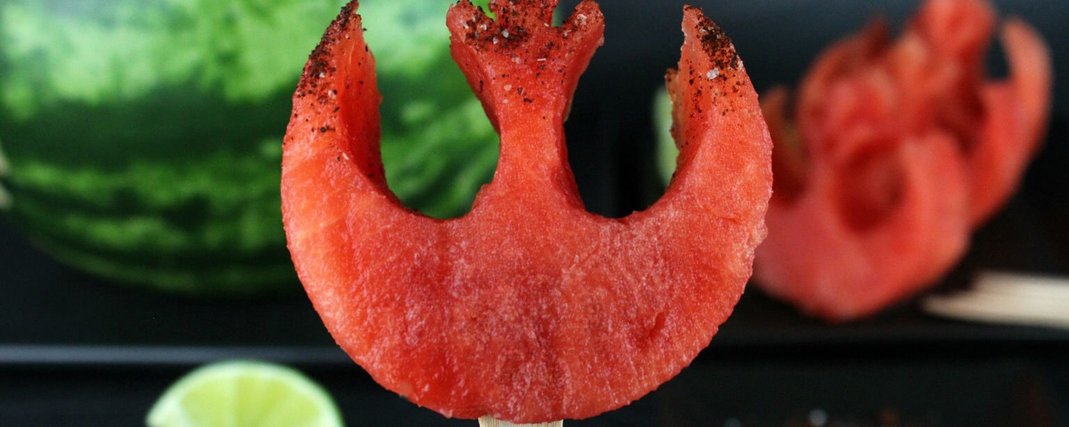 A hand holds up a Rebel Alliance Chili-Lime Melon Pop shaped in the image of the Rebellion insignia.