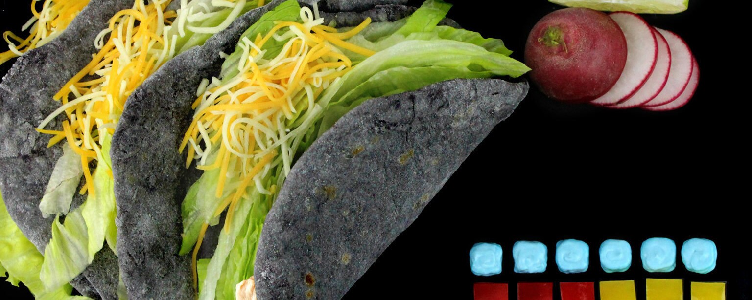 Three &quot;Grand Moff&quot; Tacos made with homemade tortillas dyed to reflect the stately gray tone of Imperial uniforms, complete with a side of blue sour cream with red and yellow peppers cut into squares to replicate the rank insignia plaque.