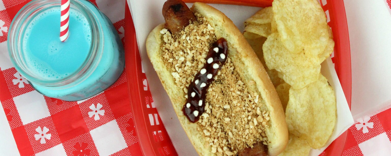 A Chewbacca-themed hot dog with chips, carrots, and blue milk.