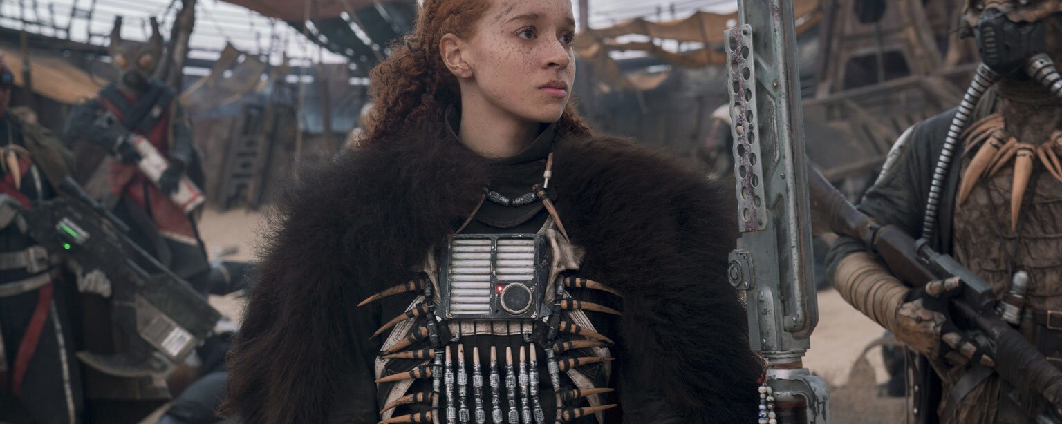 Enfys Nest stands beside her gang of Cloud Riders in front of a coaxium refinery.