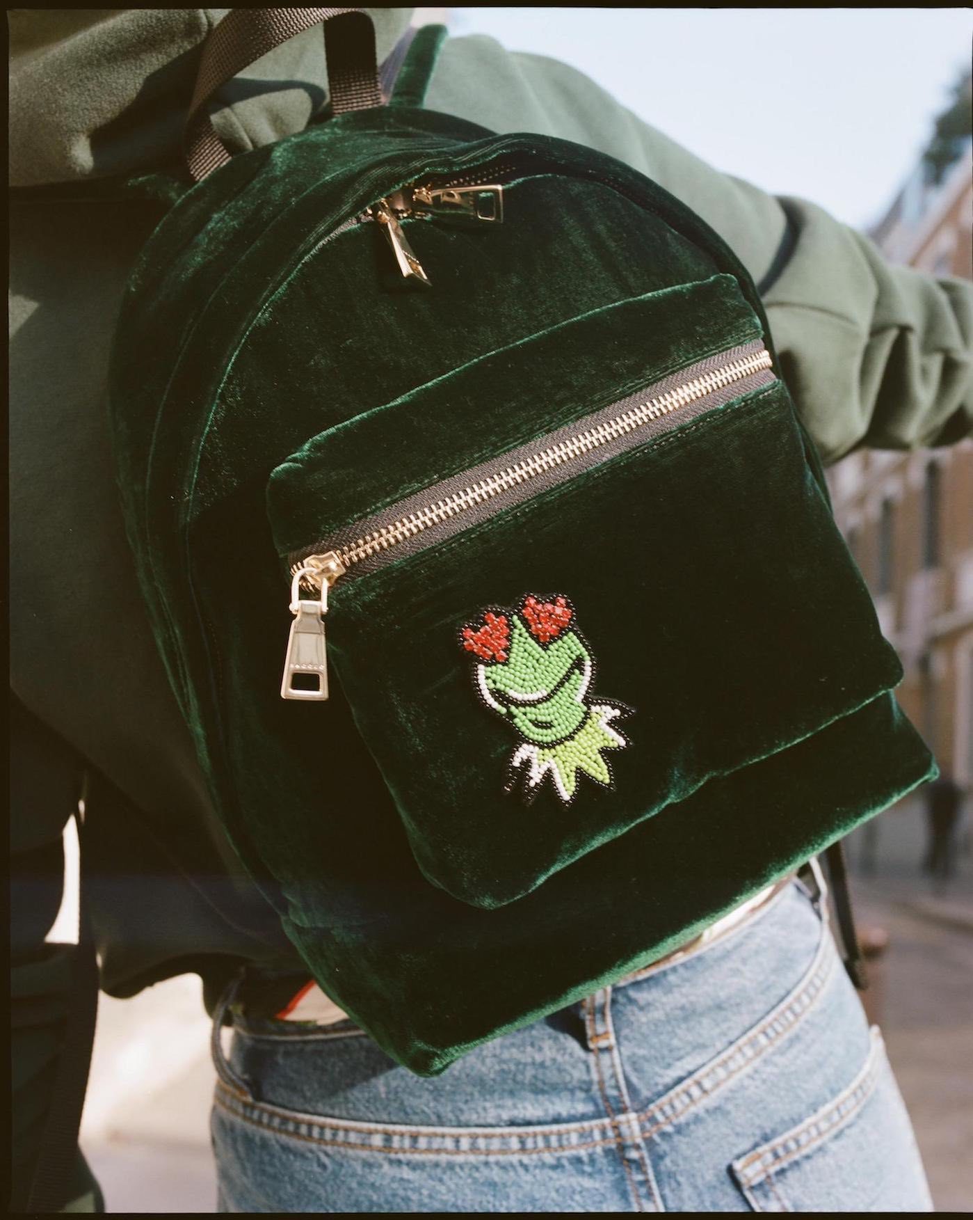 Model wearing a velvety green back pack featuring Kermit from the Sandro collection