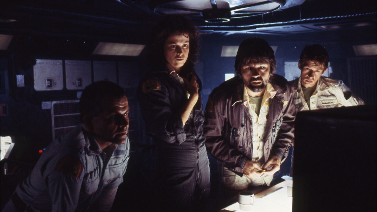 Ash (actor Ian Holm), Ripley (actor Sigourney Weaver), Dallas (actor Tom Skerritt), and Kane (actor John Hurt) staring at a computer screen from the movie "Alien."