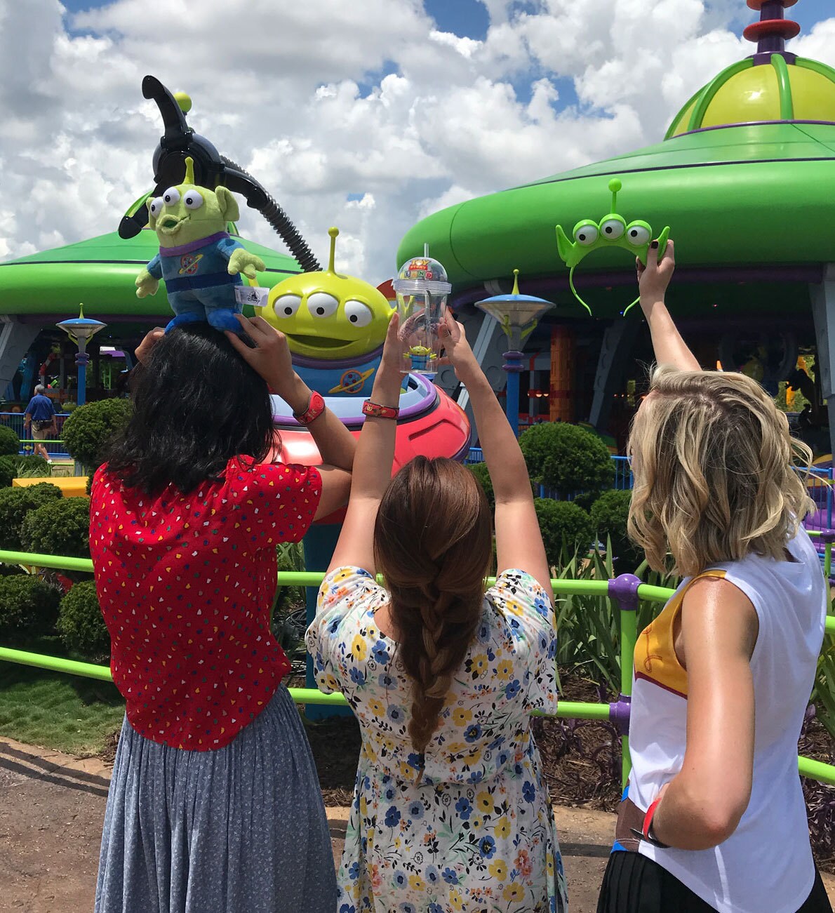 Correspondents Holding up alien merchandise in front of Alien Swirling Saucers in Toy Story Land in Walt Disney World