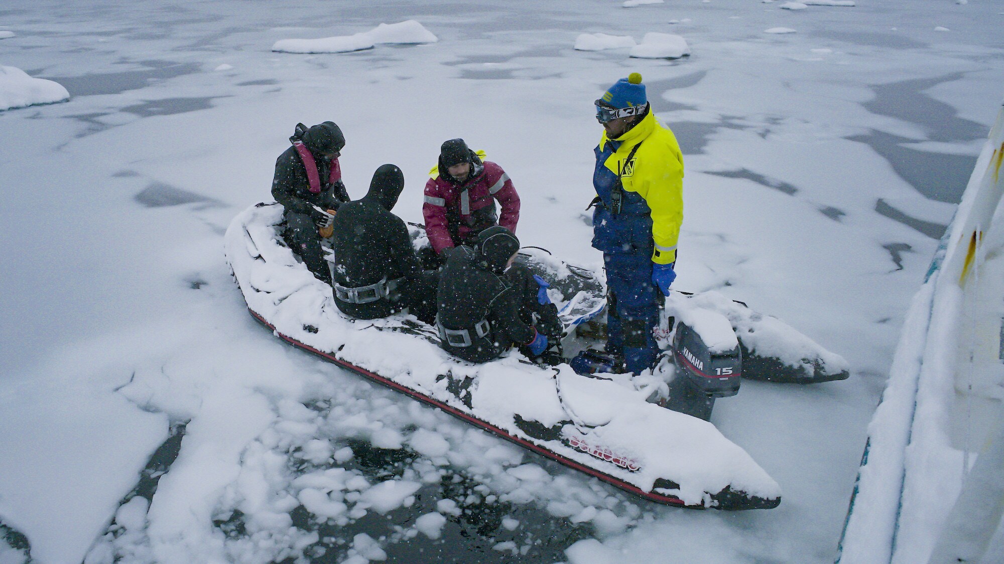 The crew sitting in a small rib boat on the iced water. (credit: National Geographic for Disney+/Will West)