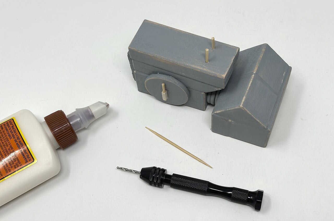 Step 23: Drill two small holes near the bottom of the AT-ST’s “face,” then glue two trimmed toothpicks inside.