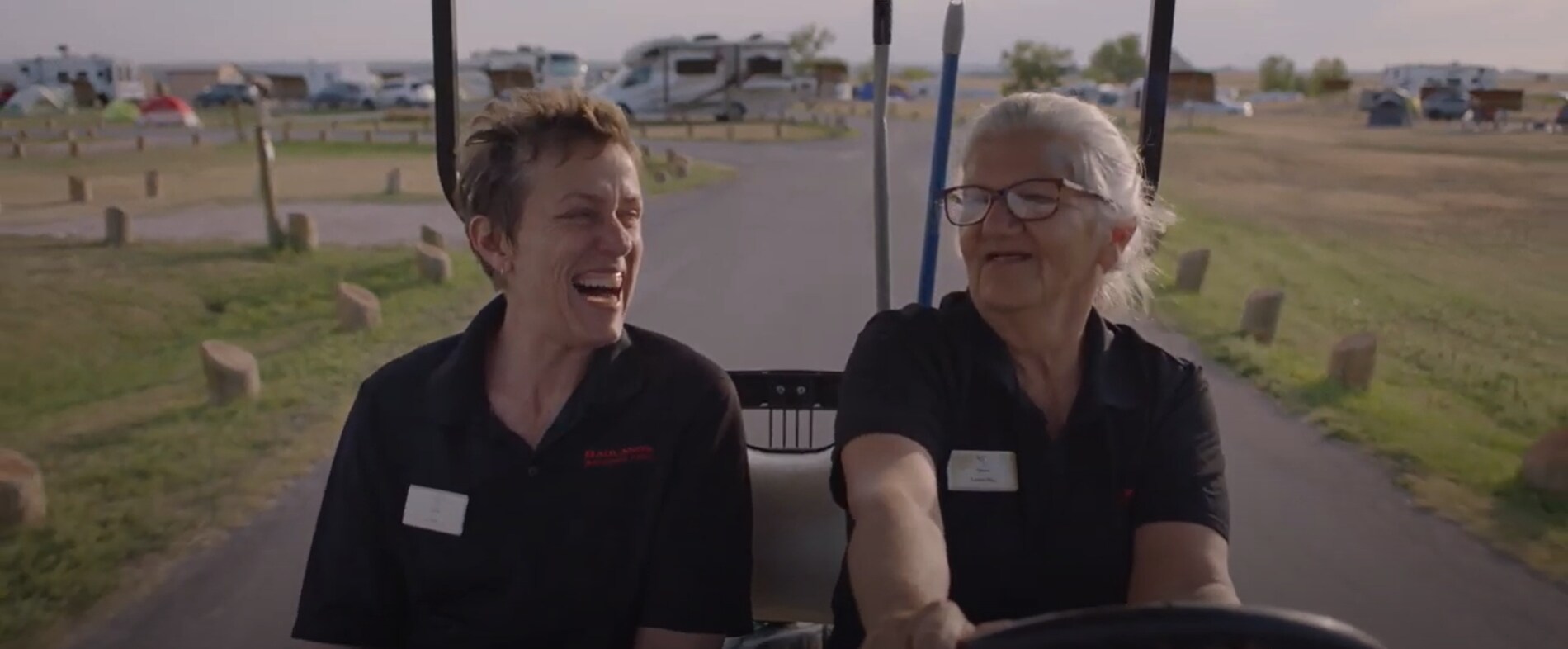 Still image on Frances McDormand and co-star on a golf cart laughing in Nomadland