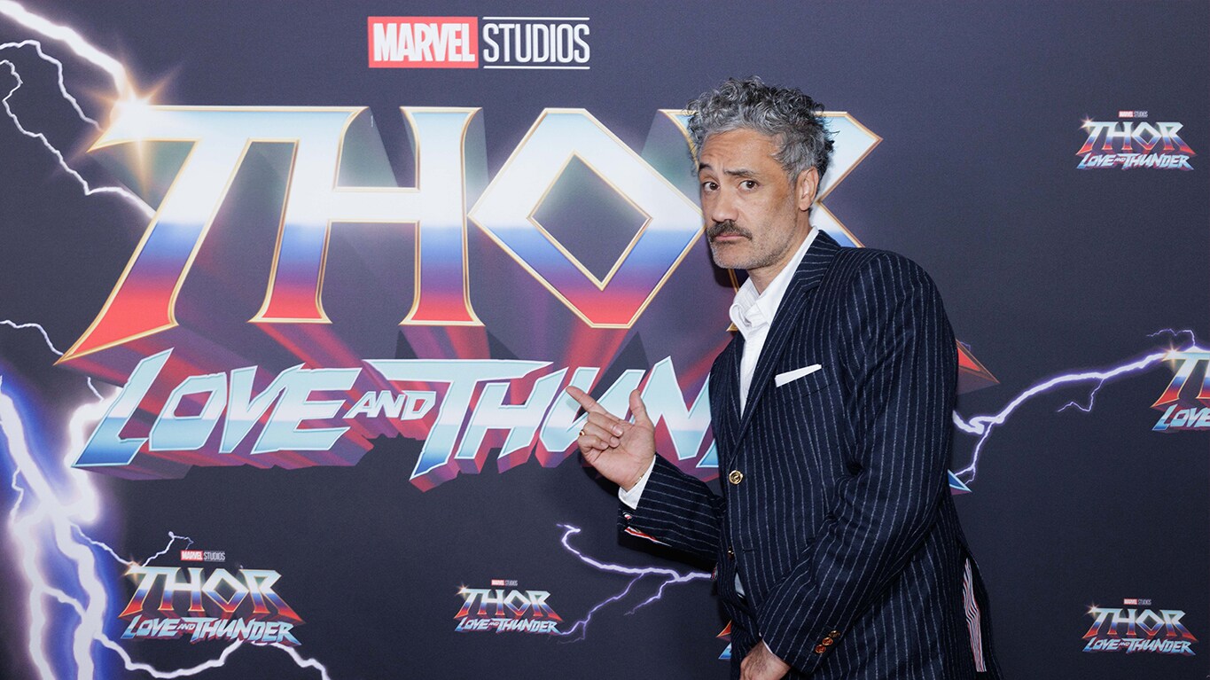 Taika Waititi in front of the 'Thor: Love and Thunder' title treatment