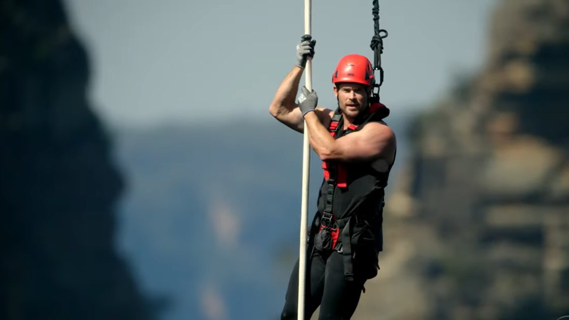 Chris Hemsworth in a harness hanging between two mountain cliffs from Limitless with Chris Hemsworth
