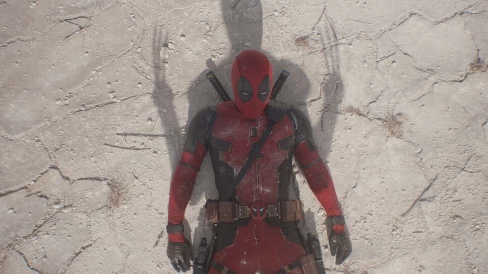 Deadpool aka Wade Wilson (actor Ryan Reynolds) laying on cracked ground in a shadow cast by Wolverine (actor Hugh Jackman) from the film "Marvel Studios' Deadpool & Wolverine".