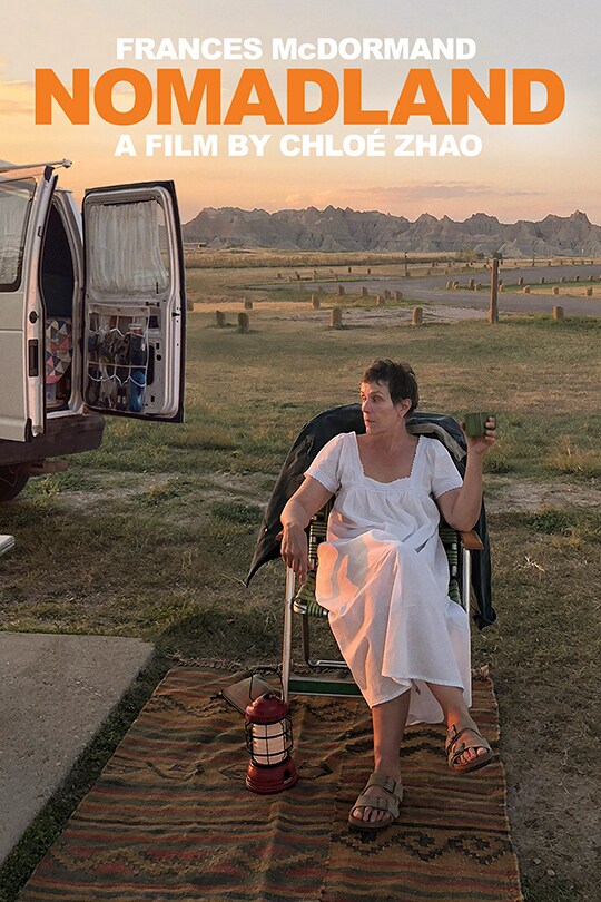 Frances McDormand as Fern sits on a chair in the open country, next to her travelling van.