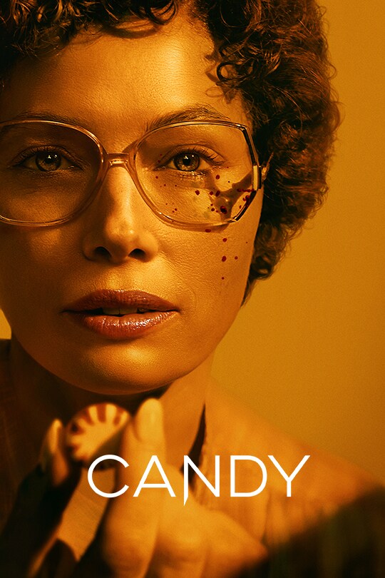 An image of Jessica Biel in the series Candy, looking at the camera with glasses styled from the 1970's, with a strong orange-hue over the image.