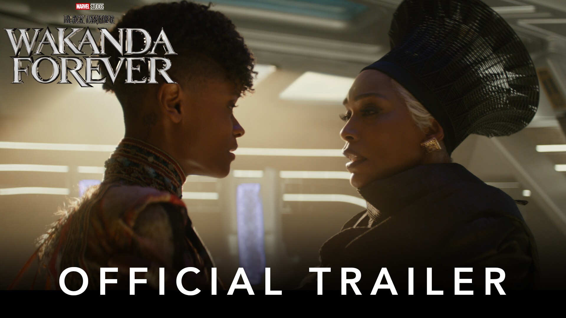The queen of Wakanda sits in her throne with two guards next to her, looking towards someone out of camera. A bright clear sky can be seen through the clean windows in the background. 'Marvel Studios’ Black Panther: Wakanda Forever' title is in the top left hand corner, 'Official Teaser' text is in the foreground.