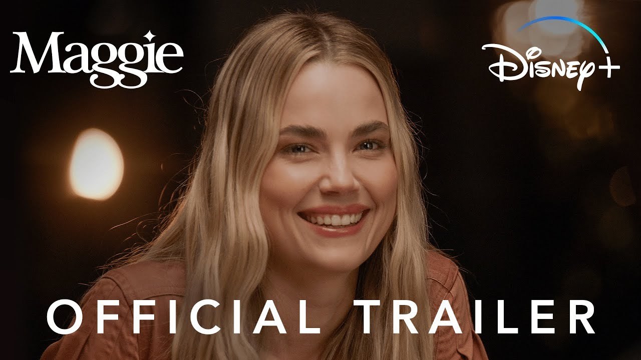 Rebecca Rittenhouse as Maggie close up, looking towards the camera with a side smile, wearing a light pink top with her dirty blonde hair. The 'Maggie' title is in the top left corner, 'Disney+' logo is in the top right and 'Official Trailer' is in the bottom of the image.