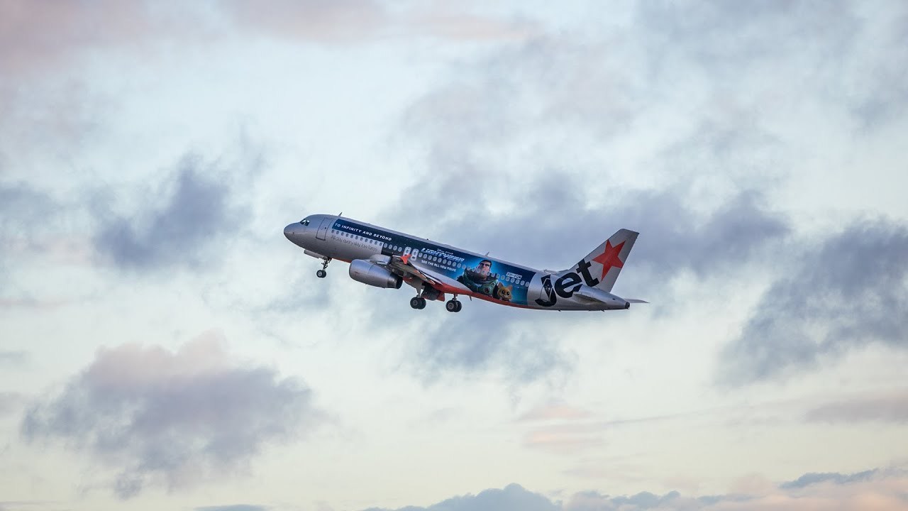 A Jetstar plan flies through the air with Lightyear themed branding on the side.