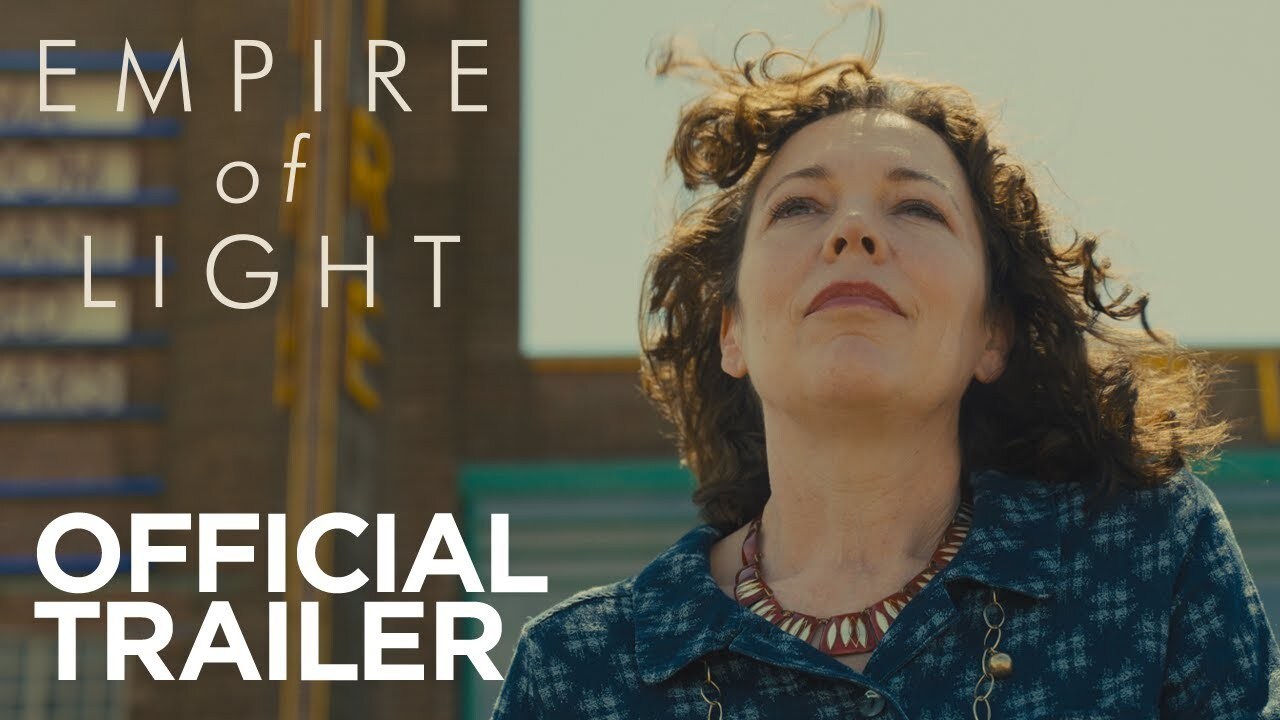 Olivia Colman looks towards the sky, with a 1980's style cinema in the background, the title 'Empire of Light' is in the top left corner, 'Official Trailer' is in the bottom left.
