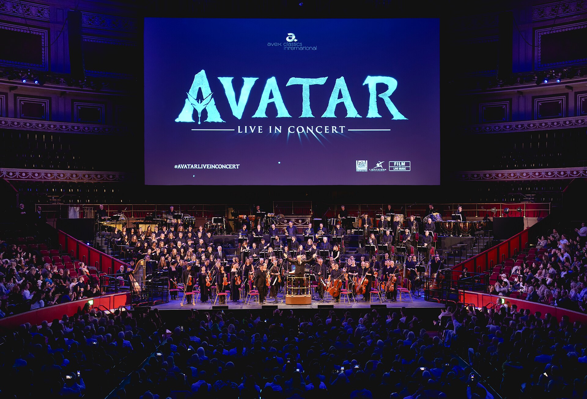 Image of symphony and audience with Avatar: Live In Concert above on a theater screen.