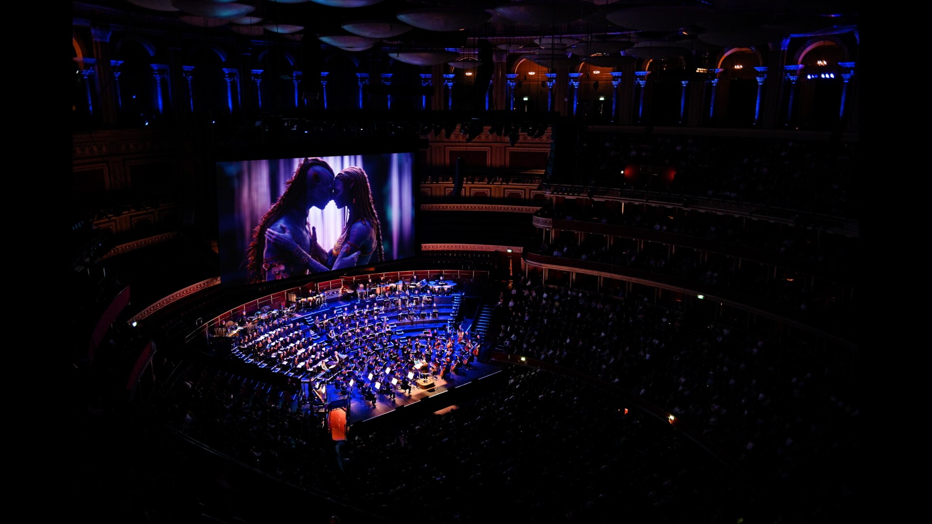 Image of a symphony and audience with characters from Avatar playing on a movie screen above.