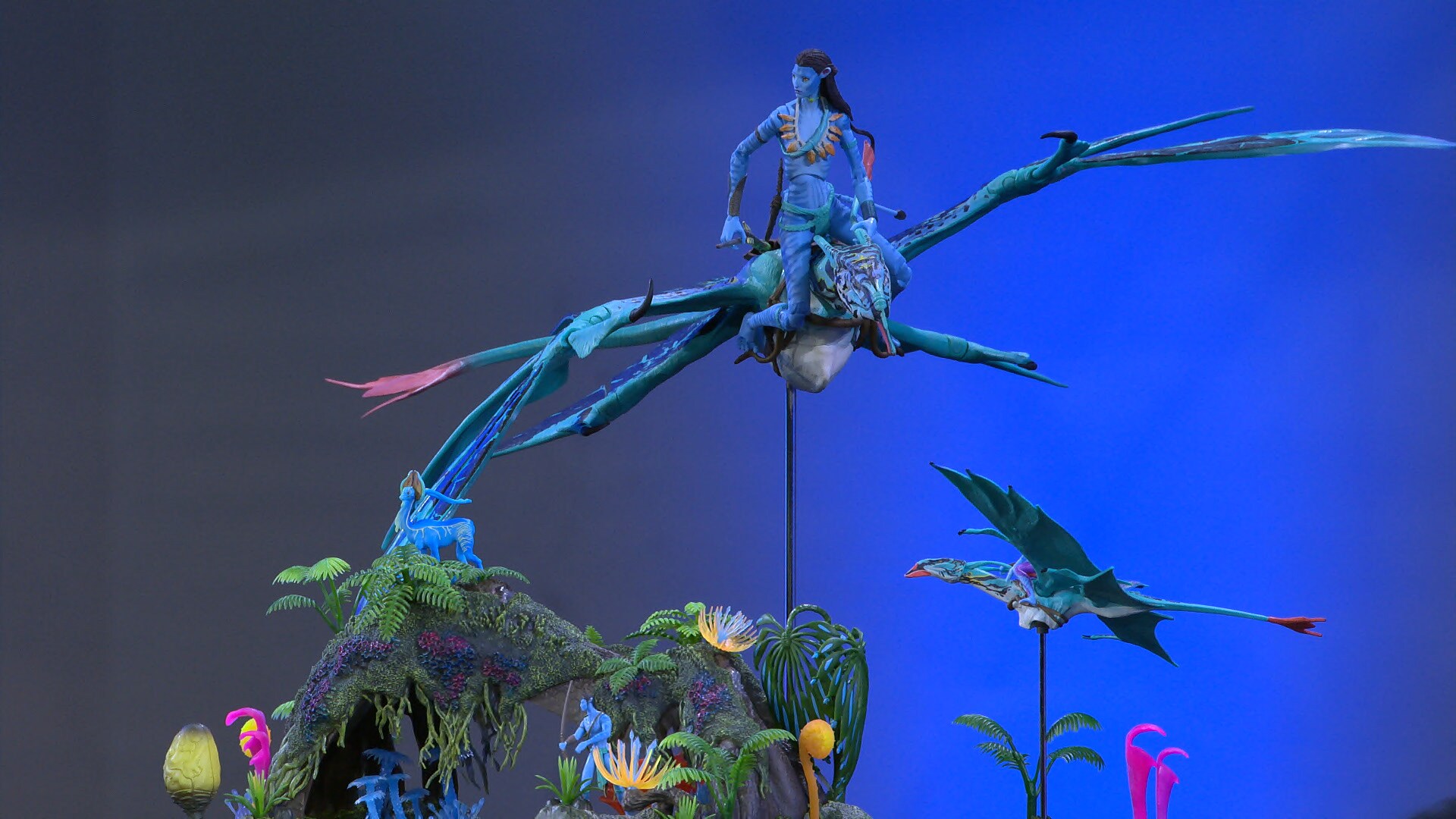 Image of a rider on a Banshee on a stand flying above fauna. There is another Banshee in the distance on a stand.