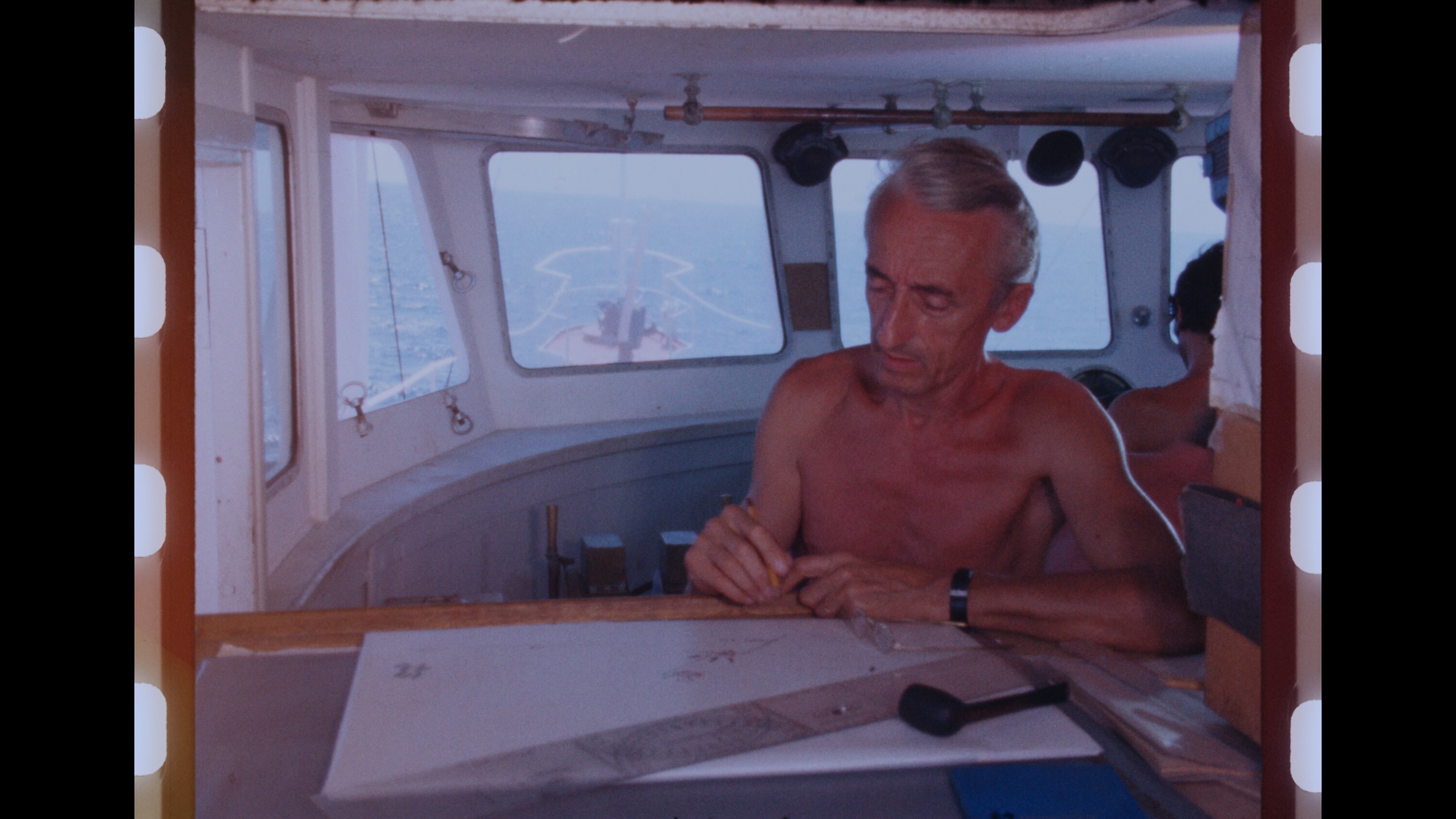 Jacques Cousteau examines navigational charts aboard his ship, Calypso. (Credit: The Cousteau Society)