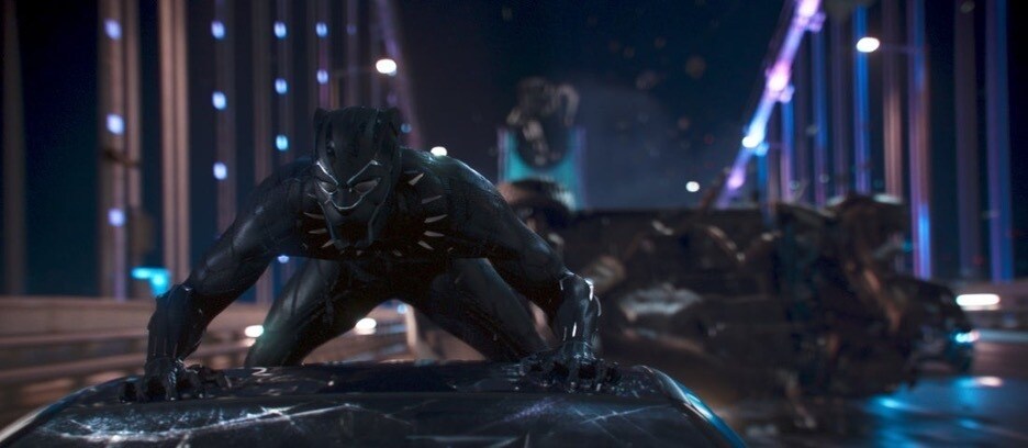 T'Challa AKA Black Panther rides down the street on top of a car in Black Panther 