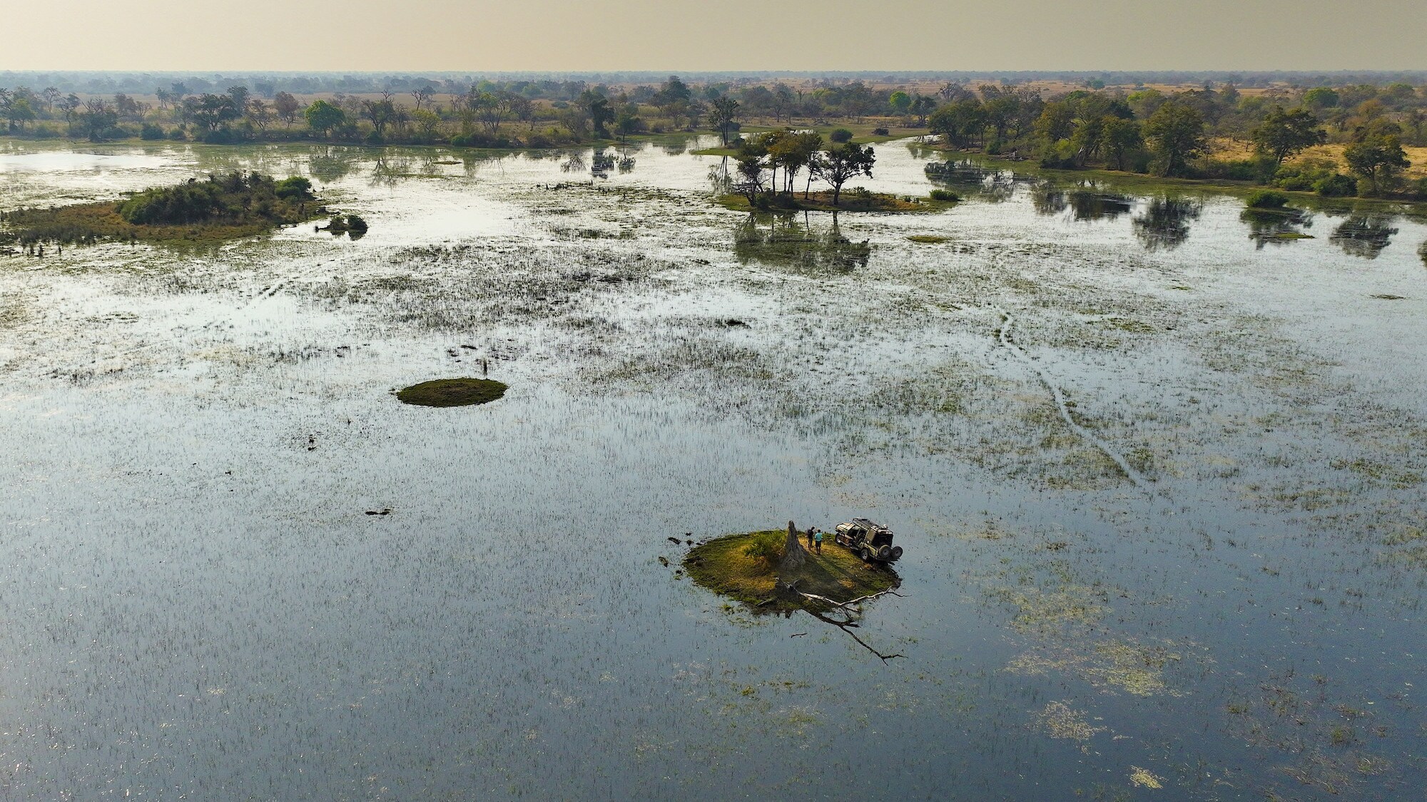 Aerial shot of the 4 wheel drive on a small 'island' surrounded by water. (National Geographic for Disney+/Bertie Gregory)