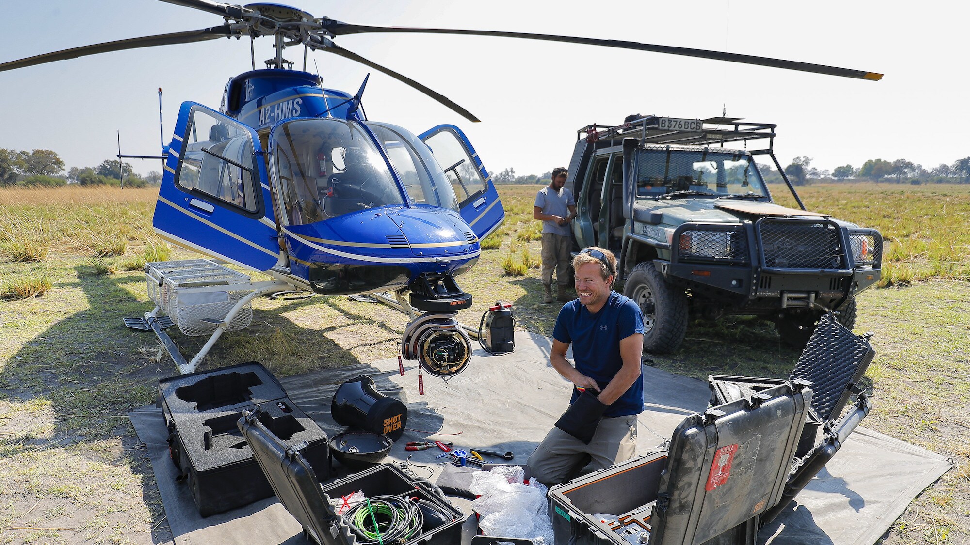 Bertie Gregory kneeling amongst cases, setting up the M1 Shotover on to the front of the helicopter. (National Geographic for Disney+/Anna Dimitriadis)