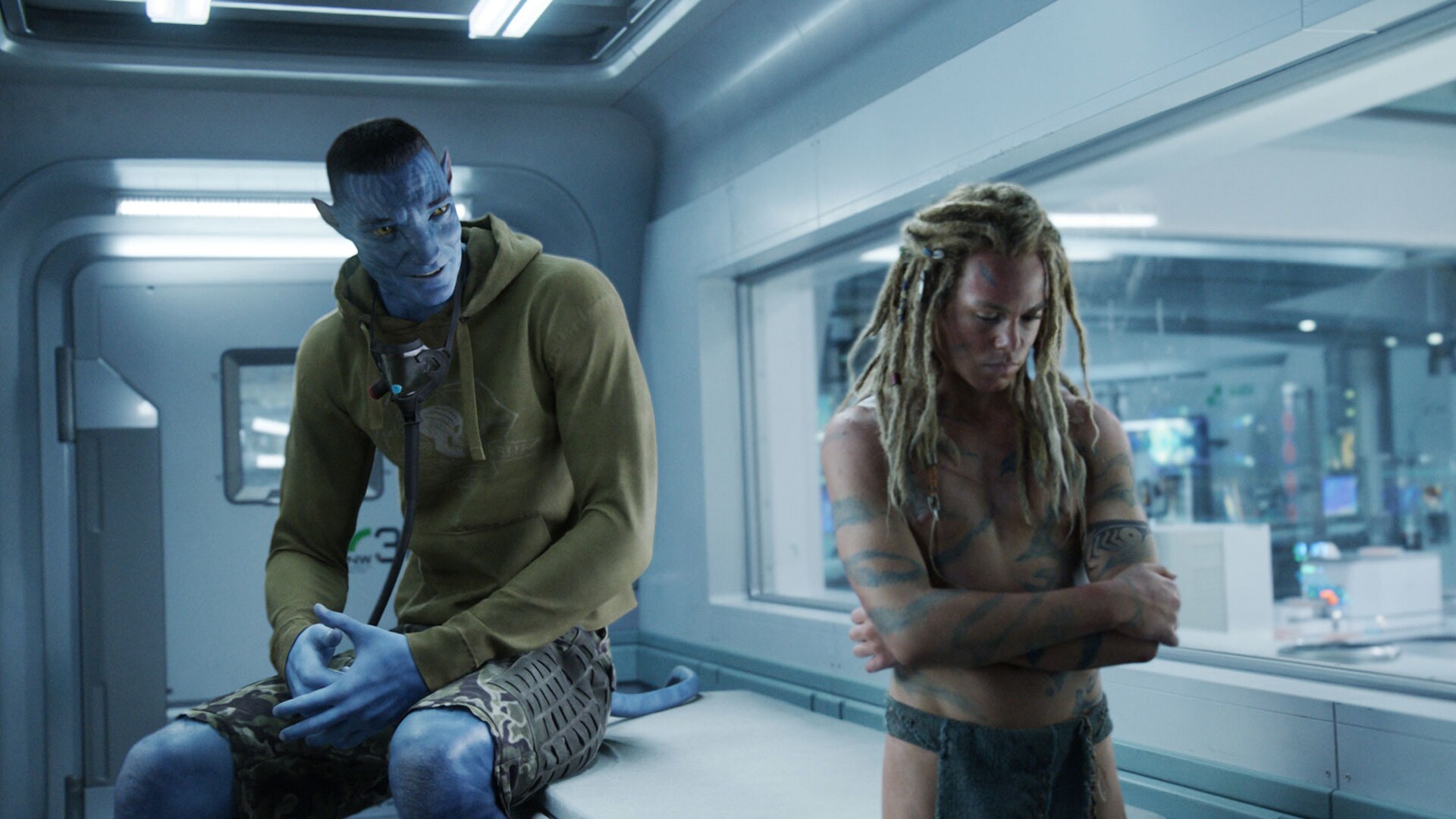 Colonel Quaritch, in recombinant form, talking to his son, Spider, who is turned away with crossed arms.