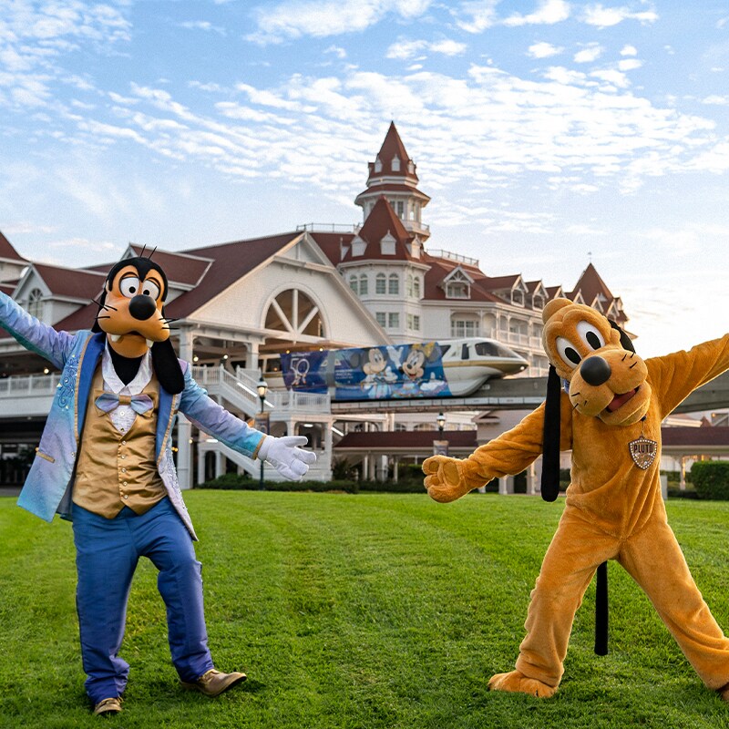 Goofy and Pluto characters pose in front of The Grand Floridian hotel.