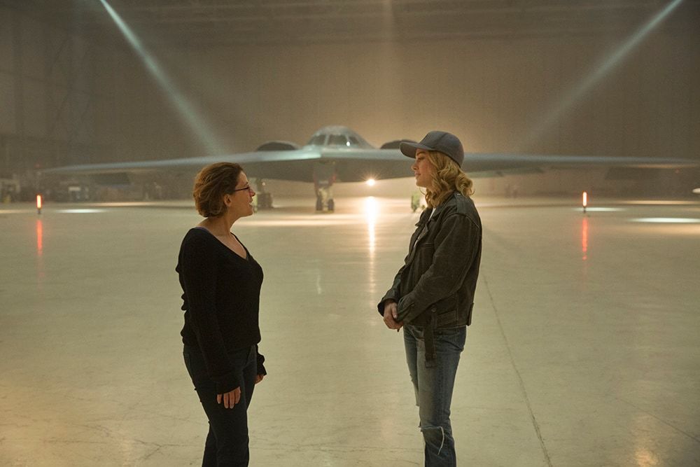 Anna Boden and Brie Larson (Captain Marvel) talking in hangar set in front of stealth bomber