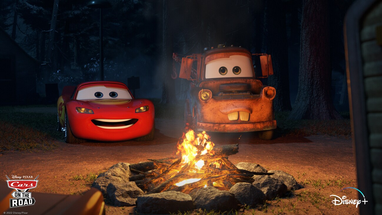 Lightning McQueen (voice of Owen Wilson) and Mater (voice of Larry the Cable Guy) in front of a campfire at night from the Disney+ Original series "Cars on the Road".