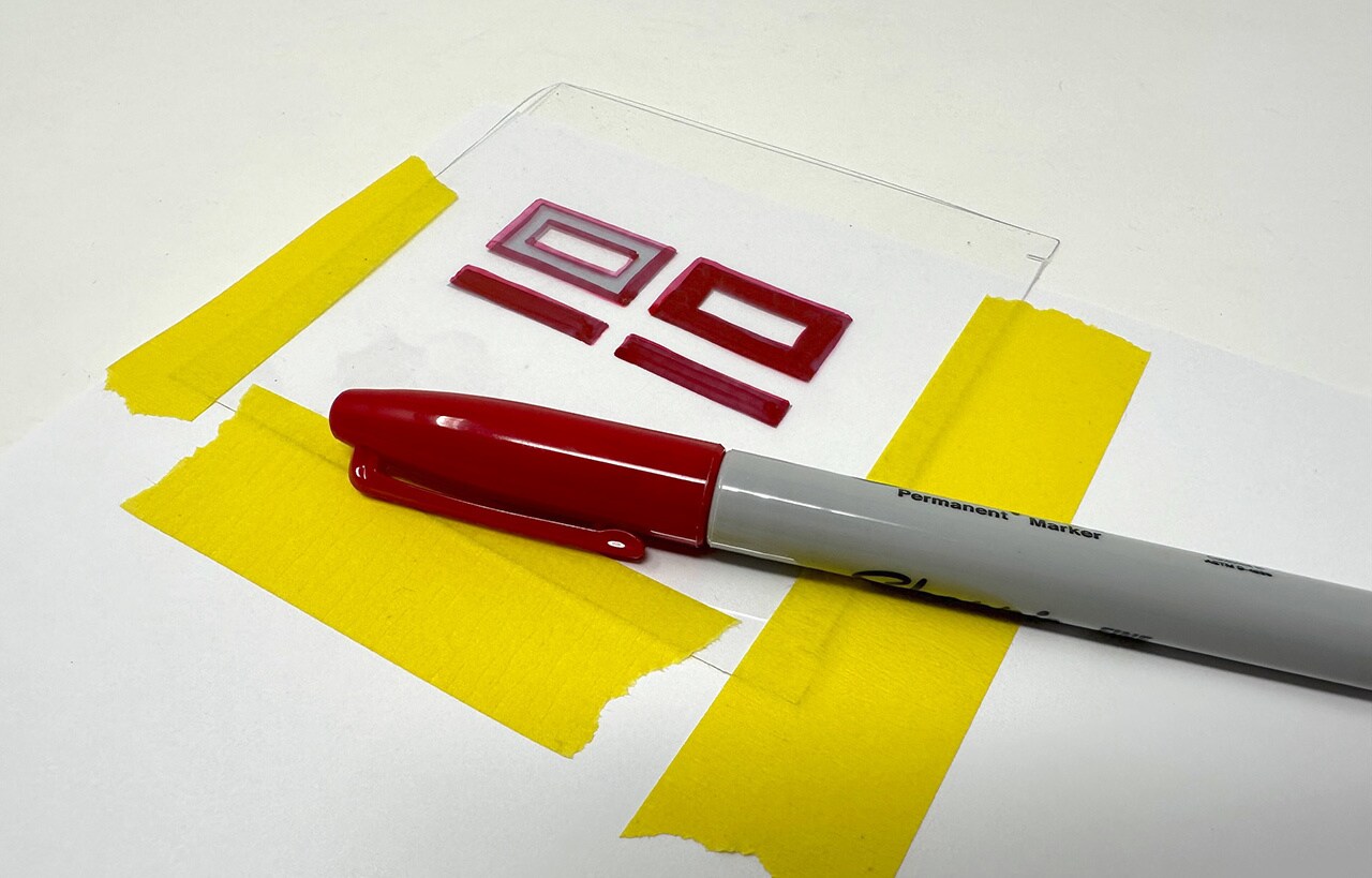 Trace the symbol with red permanent marker. Let the ink dry and remove the masking tape.