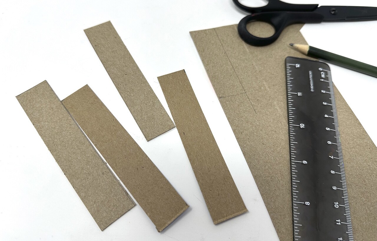 Next, cut four strips of the food packaging cardboard 4 inches long and 0.75 inches in width. Cut four more strips, 2.5 inches long and 0.75 inches in width.