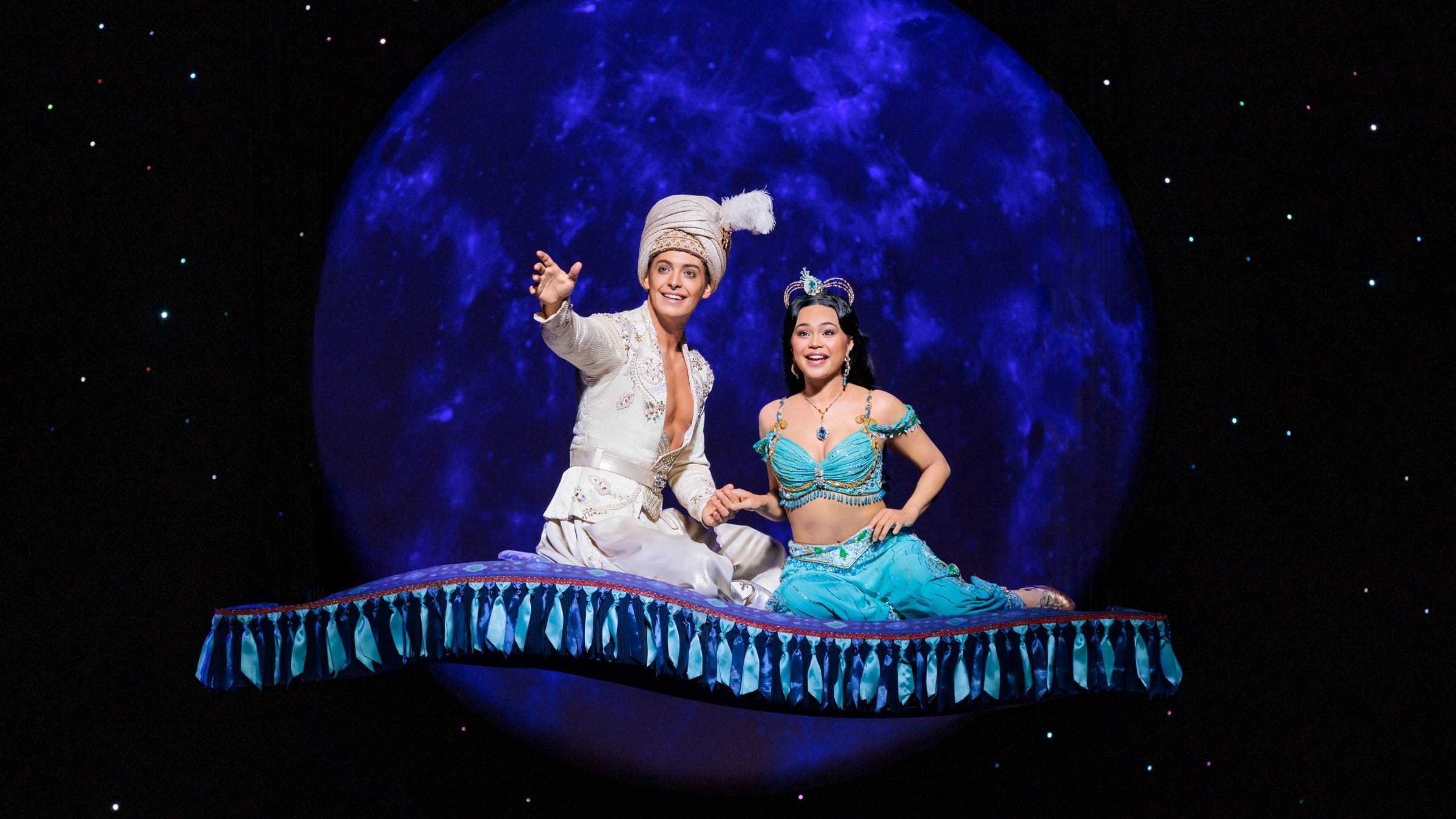 Aladdin, wie er gemeinsam mit Jasmin auf dem fliegenden Teppich sitzt und in die Ferne zeigt.