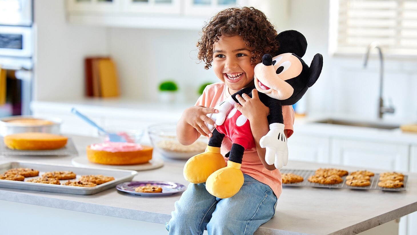 A smiling child holds a Mickey Mouse plush.