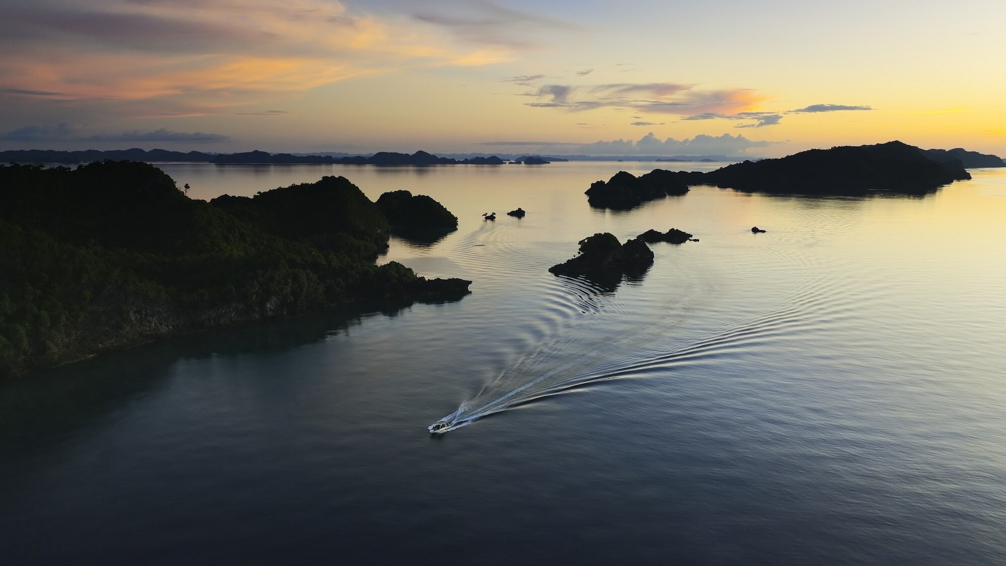 Dive boat sailing past islands.  (National Geographic for Disney+/Bertie Gregory)