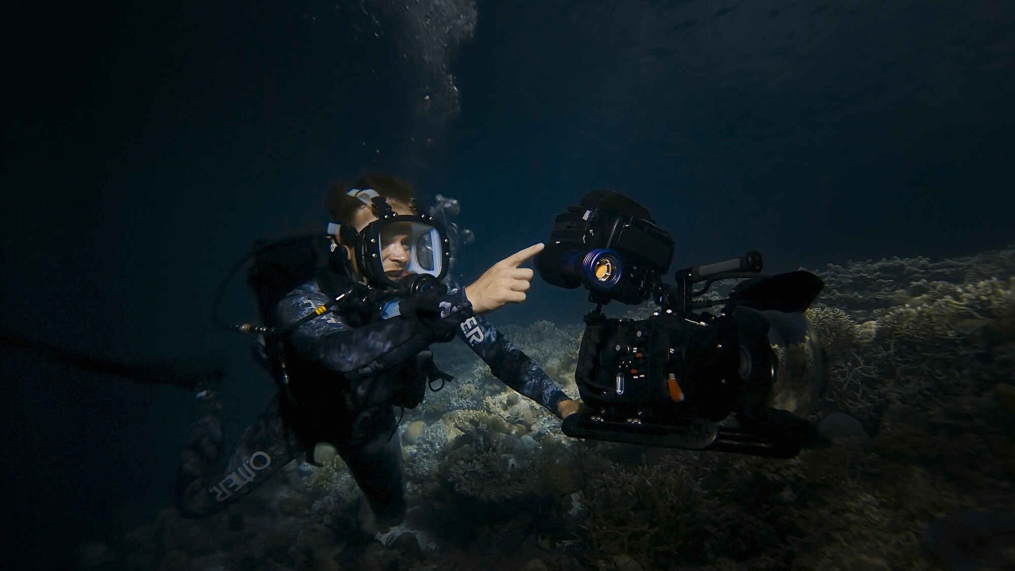 Bertie Gregory pointing towards something underwater. (National Geographic for Disney+/Dan Beecham)