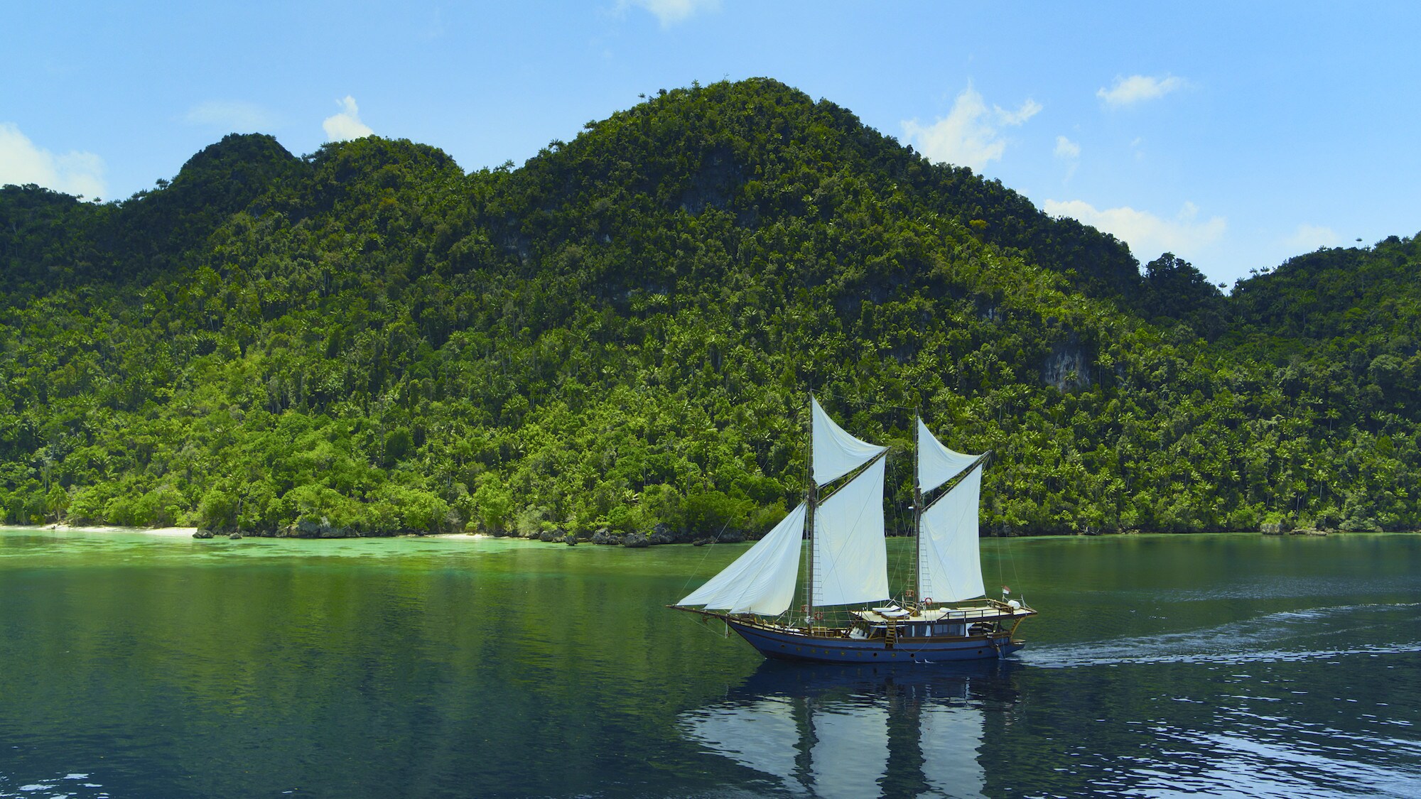 Dewata sailing with islands in the background. (National Geographic for Disney+/Bertie Gregory)