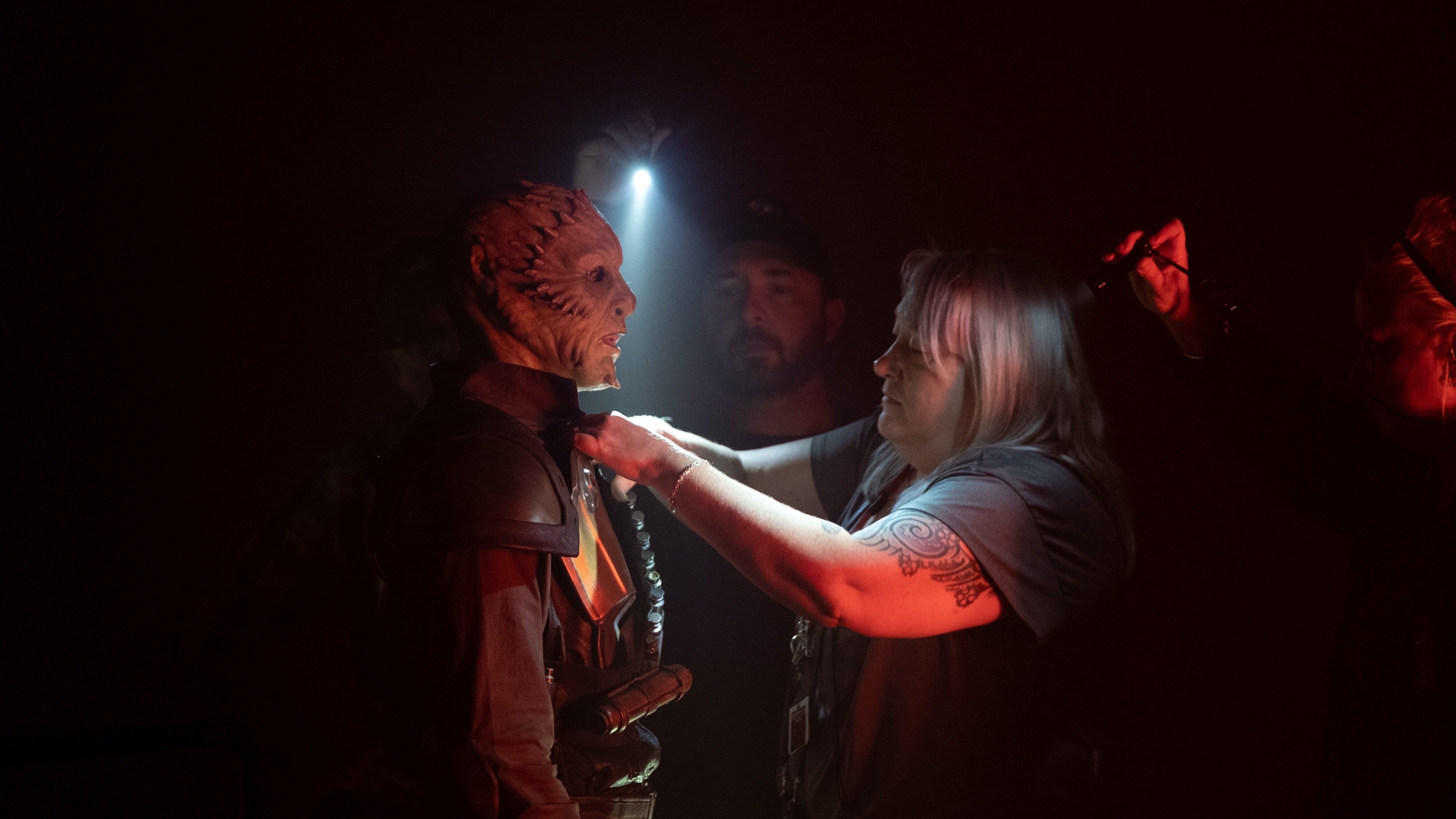 Crew member adjusting the costume for a Nutmeg Guard in THE MANDALORIAN.