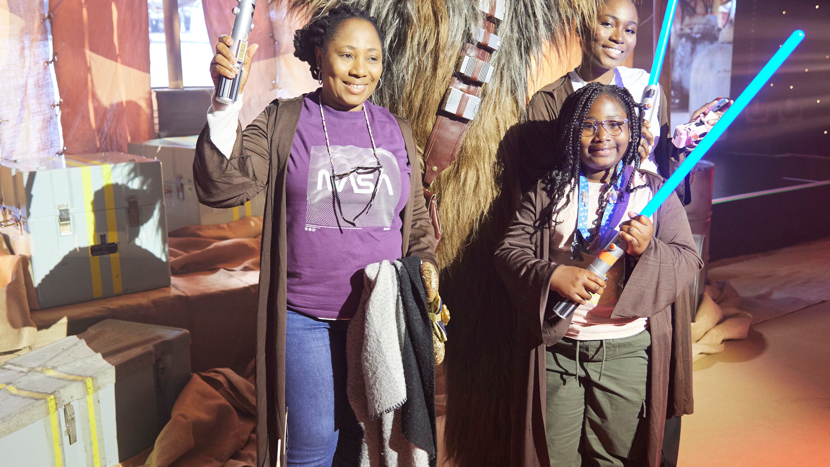 Girls posing with lightsabers posing with Star Wars' Chewbacca and BB-8 