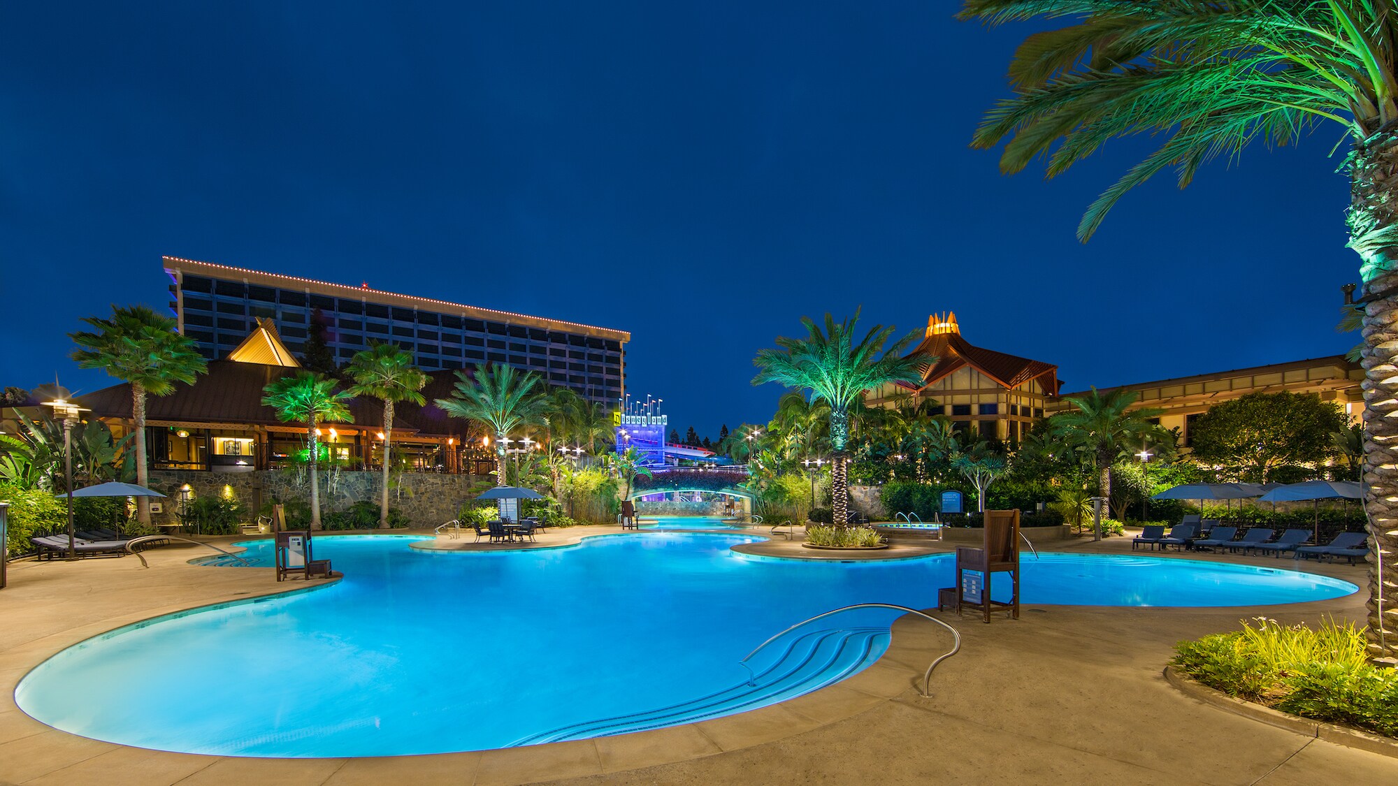 Image of the pool lit at night at the Disneyland Hotel.