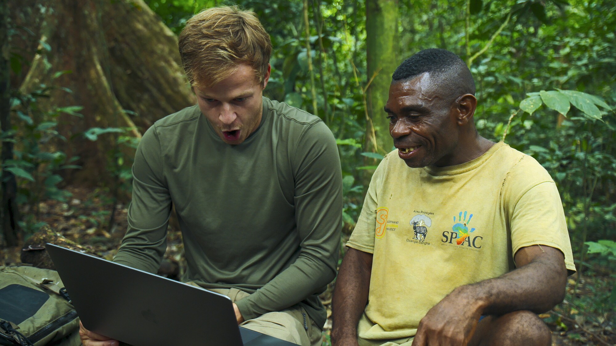 Bertie Gregory and an Ngbanda Bathelomie looking at footage on the laptop.  (National Geographic for Disney+/Mark Mclean)