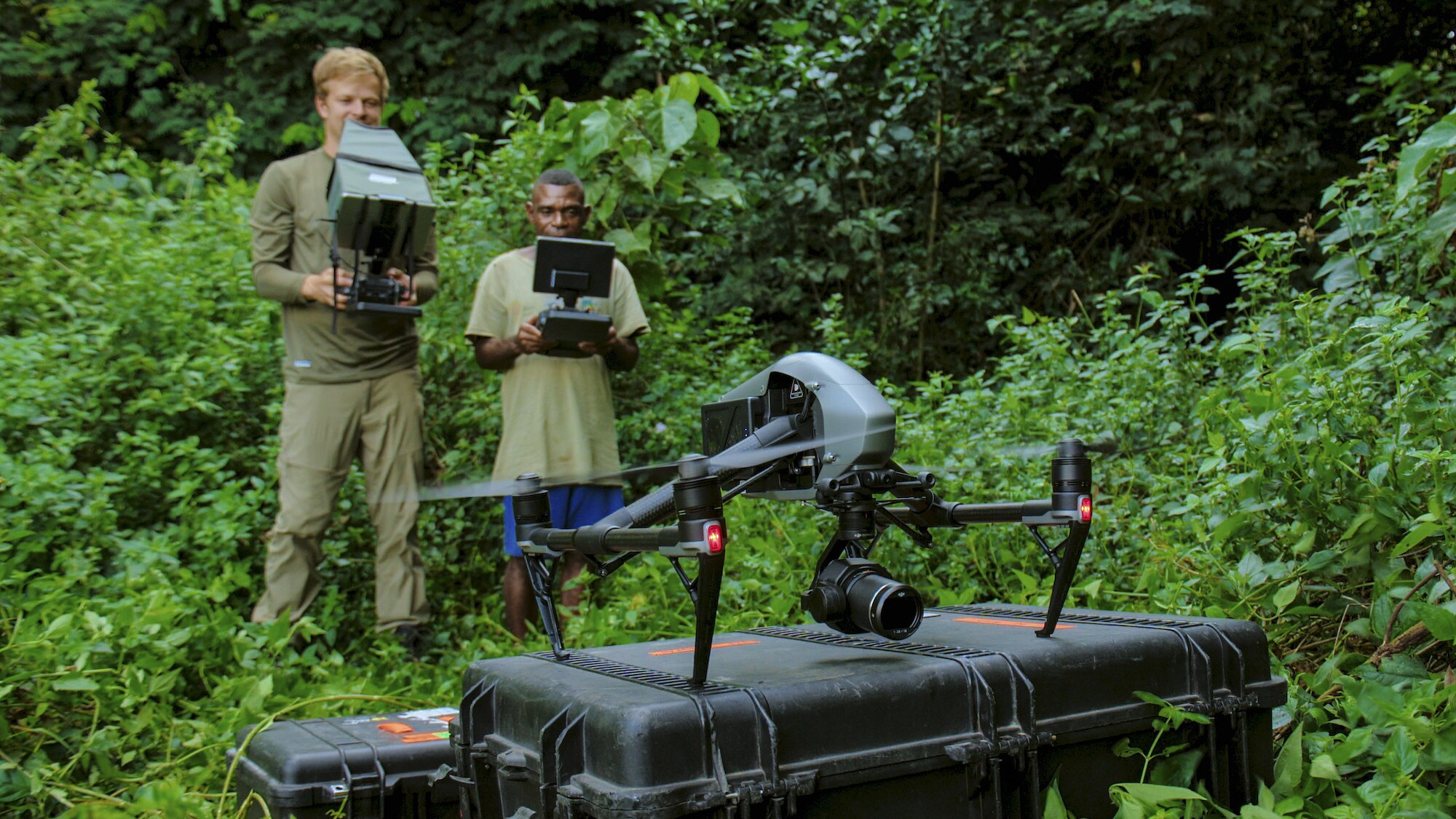 Bertie Gregory and Ngbanda Bathelomie with the drone in foreground about to take off.  (National Geographic for Disney+/Mark Mclean)